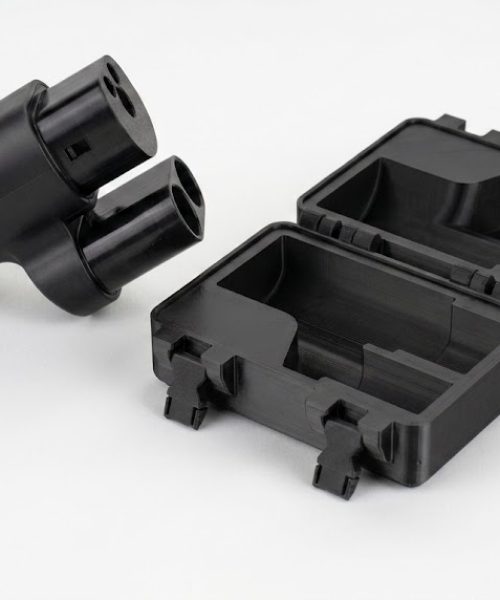 Sort CCS2 adapter vist ved siden af åben 3D-printet transportkasse